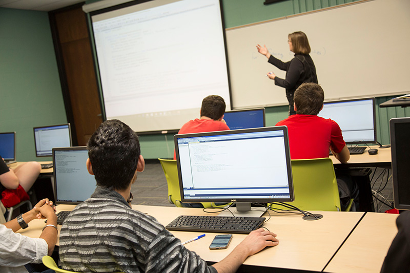 Teacher looking at overhead with students in computer class
